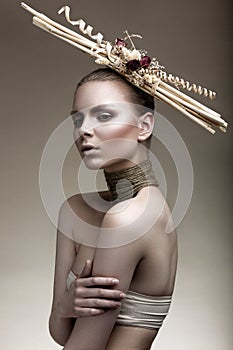 Beautiful girl with a bronze skin, pale makeup and unusual accessories. Art beauty image. Beauty face. photo