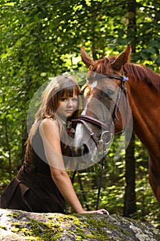 Beautiful girl and brown horse portrait in mysterious forest