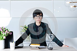 Beautiful girl, brunette in a suit and glasses, boss, looks demandingly at the camera with a serious face. Leader, chief of