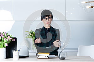 Beautiful girl, brunette in a suit and glasses, boss, looks demandingly at the camera with a serious face. Leader, chief of