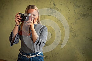 Beautiful girl with a camera in her hands, on a blurred background, a woman takes pictures