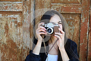 Beautiful girl with a camera on vintage wooden door background