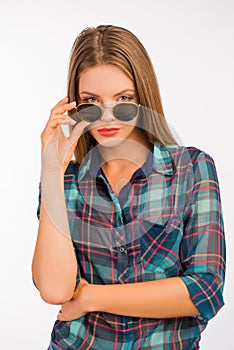 Beautiful girl in a checkered shirt holding sunglasses with one hand