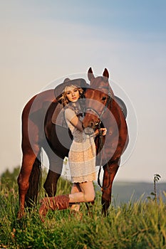 Beautiful girl with chestnut horse in evening field