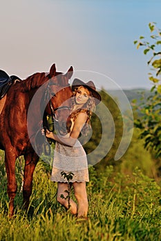 Beautiful girl with chestnut horse in evening field