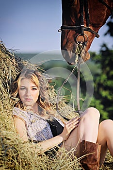 Beautiful girl with chestnut horse in stack of hay