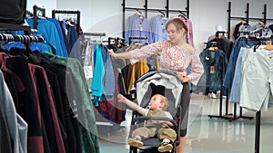 Beautiful girl with a child goes to the store and chooses clothes