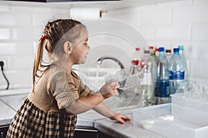 Beautiful girl child puts a plastic bottle in a recycling box. A child takes part in sorting plastic for recycling. The