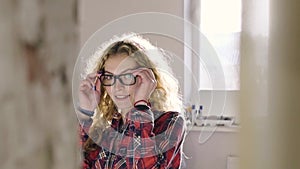 Beautiful girl cleans the bed in the morning and wears glasses