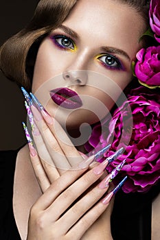 Beautiful girl with colorful make-up, flowers, retro hairstyle and long nails. Manicure design. The beauty of the face.