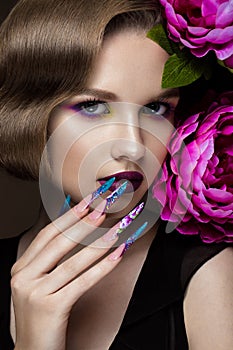 Beautiful girl with colorful make-up, flowers, retro hairstyle and long nails. Manicure design. The beauty of the face.