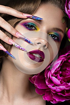 Beautiful girl with colorful make-up, flowers, retro hairstyle and long nails. Manicure design. The beauty of the face. photo