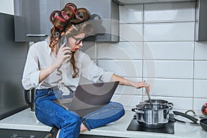 Beautiful girl is cooking and  talking on a smartphone.