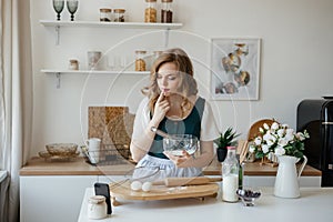 Beautiful girl cooks and looks at the recipe on the smartphone