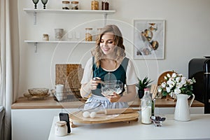 Beautiful girl cooks and looks at the recipe on the smartphone