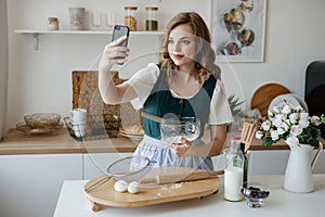 Beautiful girl cooks and looks at the recipe on the smartphone