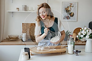 Beautiful girl cooks and looks at the recipe on the smartphone