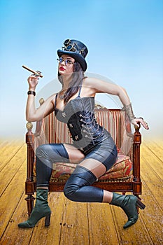 Beautiful girl in a corset, a fedora hat and steampunk welding glasses, with a cigar in her hand