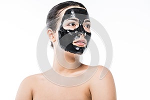 beautiful girl in cosmetic black clay facial mask looking away