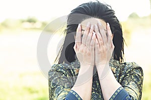 Beautiful girl covers her face with her hands