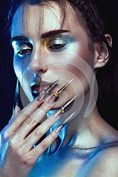 Beautiful girl with creative golden and silver glitter make-up, long nails art. beauty face.