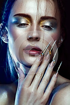 Beautiful girl with creative golden and silver glitter make-up, long nails art. beauty face. photo