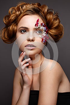 Beautiful girl with creative make-up with floral appliques. The model in the style of romantic with flower petals around her