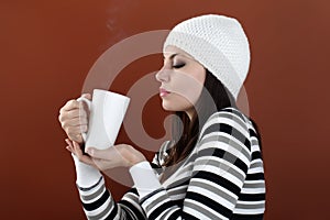 Beautiful girl with cup in hands to keep warm drink