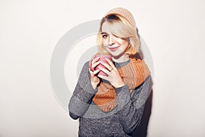 Beautiful girl With Cup of Tea or Coffee in hat, sweater, scarf. Woman`s hand holding a pink cup of coffee. Romantic Winter