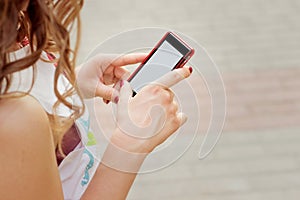 Beautiful girl with curly hair standing on the street in phone in hand, sends an SMS message reads