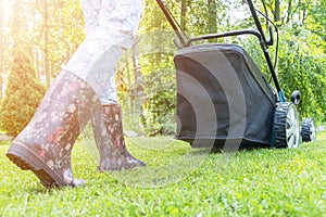 Beautiful girl cuts the lawn. Mowing lawns. Beautiful woman lawn mower on green grass. Mower grass equipment. Mowing gardener care