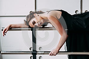 Beautiful girl dancer. tired girl dancer. girl ballerina or dancer in a black dress lying on a ballet barre