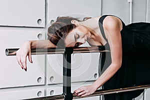 Beautiful girl dancer. tired girl dancer. girl ballerina or dancer in a black dress lying on a ballet barre