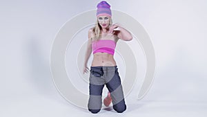 Beautiful girl dancing hip-hop in colorful clothes, studio. Hip-hop dancer girl posing making acrobatic moves on the ground.