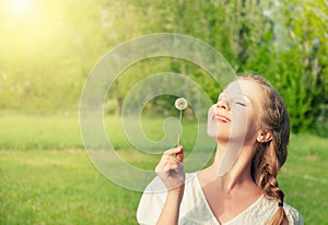 Beautiful girl with dandelion enjoying sun