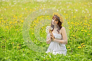 Beautiful girl with dandelion flowers in green field