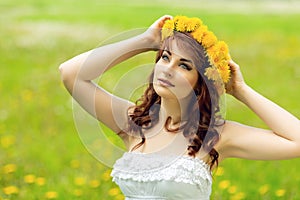 Beautiful girl with dandelion flowers in green field