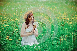 Beautiful girl with dandelion flowers in green field