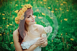 Beautiful girl with dandelion flowers in green field