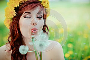 Beautiful girl with dandelion flowers in green field