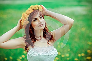 Beautiful girl with dandelion flowers in green field