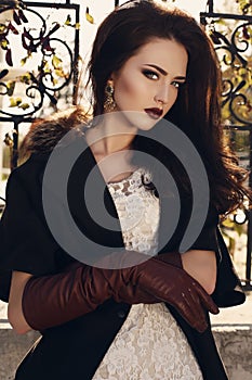 Beautiful girl with dark hair in elegant coat and leather gloves