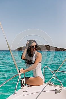 Beautiful girl with dark hair in luxurious bikini relaxing on yacht