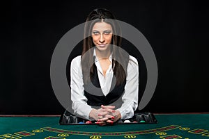 The beautiful girl, dealer, behind a table for poker photo