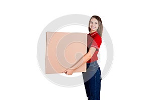 Beautiful girl is delivering a huge parcel to a customer. Smiling woman in work clothes is holding a box isolated on white