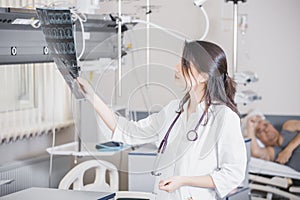 Beautiful girl doctor in a white coat examines X-ray photo of the patient to identify the problem. Professional conversation, cons