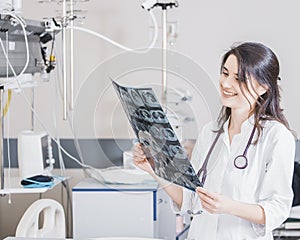 Beautiful girl doctor in a white coat examines X-ray photo of the patient to identify the problem. Professional conversation, cons