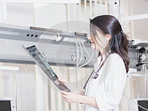 Beautiful girl doctor in a white coat examines X-ray photo of the patient to identify the problem. Professional conversation, cons