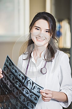 Beautiful girl doctor in a white coat examines X-ray photo of the patient to identify the problem. Professional conversation, cons