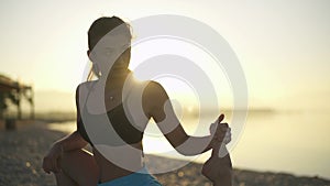 Beautiful girl doing a warm-up by the sea. Sports, yoga, sunrise.